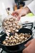 Mushroom - This is the image of the mushrooms being poured into the pan on the stove by the chef in the kitchen