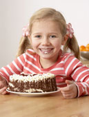 Eating Cake - This is the photo of the young girl in the kitchen eating cake and making a mess smiling.