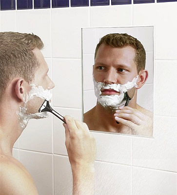 see face in mirror - The man is making sure he do not get hurt while shaving.