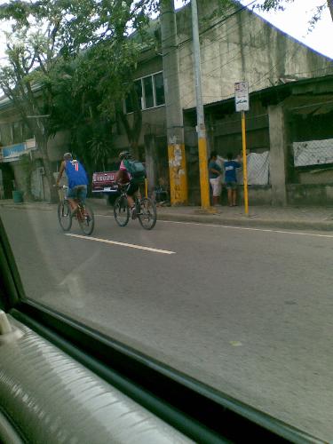 bicycle riders - bicycle riders -- one wearing a protective head gear while the other only wears a cap