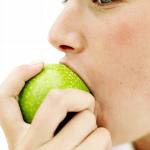 Eating - Someone eating a green apple.