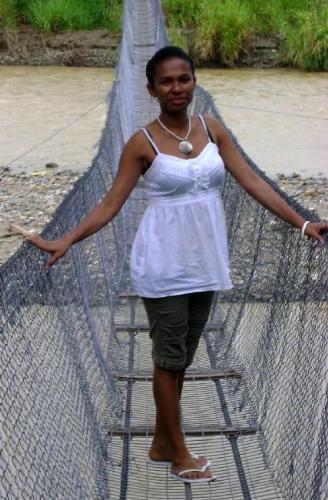 YOung lass of PNG crossing a wire bridge - Modern young lass crossing over a tradtional wire bridge in a rural PNG.