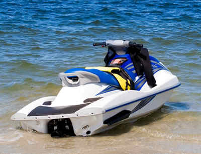 vihicles - a jetski in the seashore. the jetski's color is white with some blue on it.