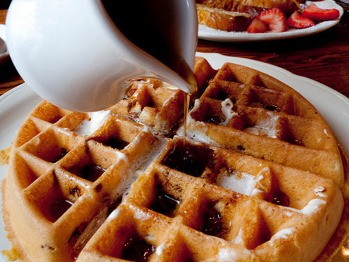 syrup drops - a delightful belgian waffle with maple syrup being poured on top