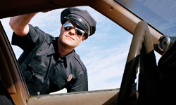 A Cop leaning into a car window to ask for license - This picture depicts the act of issuing a speeding ticket, a curse for office-goers the world over.