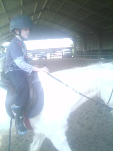Older son looking on while riding - Here is my son on his own, walking around the court with the horse.