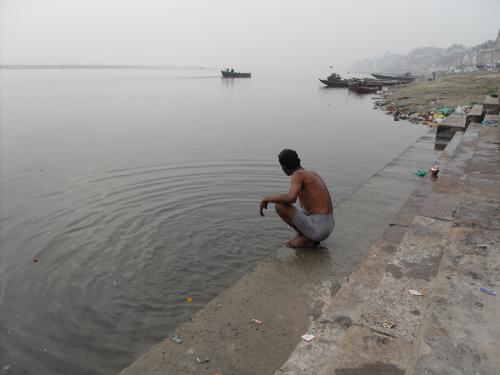 apathy - This is a photo of a man sitting alongside the bank of the river ganges and u can c the garbage pile on the sides of the bank of the river even though it is considered sacred.