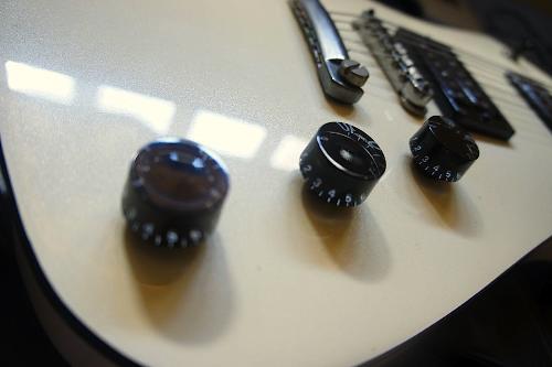 guitar - A white guitar with black circular knobs.