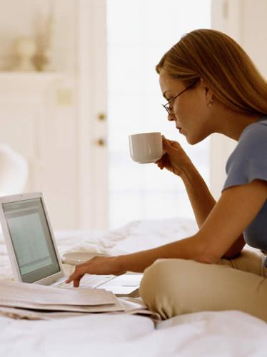 Online - A woman drinking coffee and spending time online.