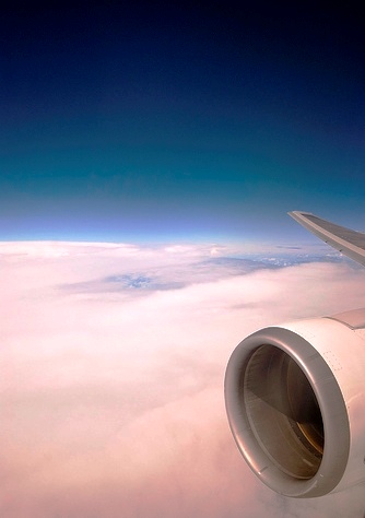 exhaust - a plane polluting exhaust up in the air beyond the clouds above the earth and seas.