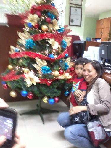 the office tree - this is the office christmas tree..thats my officemate and her son..i cant find other pics of the tree right now..well thats about to change - its looks i mean
