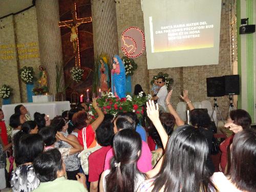 devotion - The statue of Our Lady of Guadalupe during the annual fiesta surrounded by devotees.