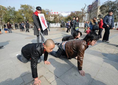 performance art - Three men crawl on the ground while chained by a woman during a contraversial performance show in Wuhan, capital of Central China's Hubei Province, on Feburary 8, 2012.