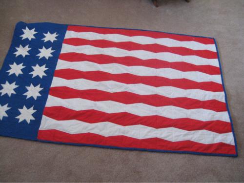 American Flag Quilt - twin size - Just finished my American Flag quilt for my grand son. Has 13 strips, but had to 'alter' the stars! They are done with the 'flying geese' template and the strips are done with a 5' tumbler template. It is twin bed size and I'll have you know it is what could be considered 'quilt in a day'. I took 2 days, but about 8 hours each day off and on!