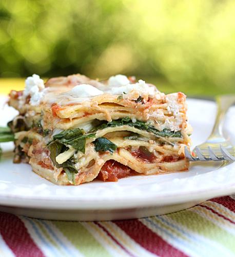 Spinach and Goat Cheese Lasagna - This picture shows a piece of spinach and cheese lasagna. it has lots of tomato sauce and cheese melted over the sides and looks absolutely delicious.