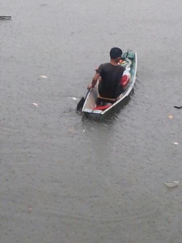 Braving the flood by boat - A man manage to brave the flood by boat. He is out to rescue some families who are up there in their roof waiting for salvation.