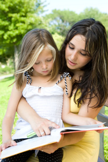 An Au Pair reading with a child in her care - See how attentively this Au Pair is reading with the child placed within her care,