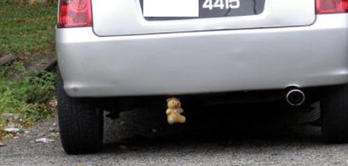 Teddy bear hanged at car exhaust - Teddy bear being hanged below the car near the exhaust.