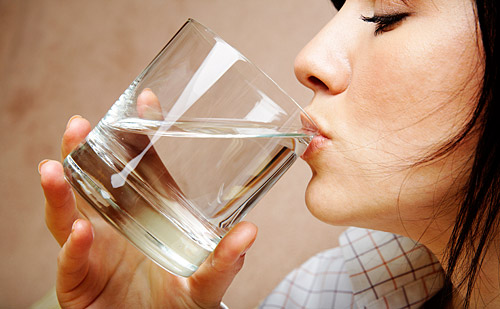 woman drinking water - 'Dehydration takes its toll on our brains by increasing stress hormones, which in turn reduces cognitive function. Dr. Amen recommends drinking half of your weight in water ounces daily—in other words, if you weigh 160 pounds, drink 80 ounces of water daily.'
