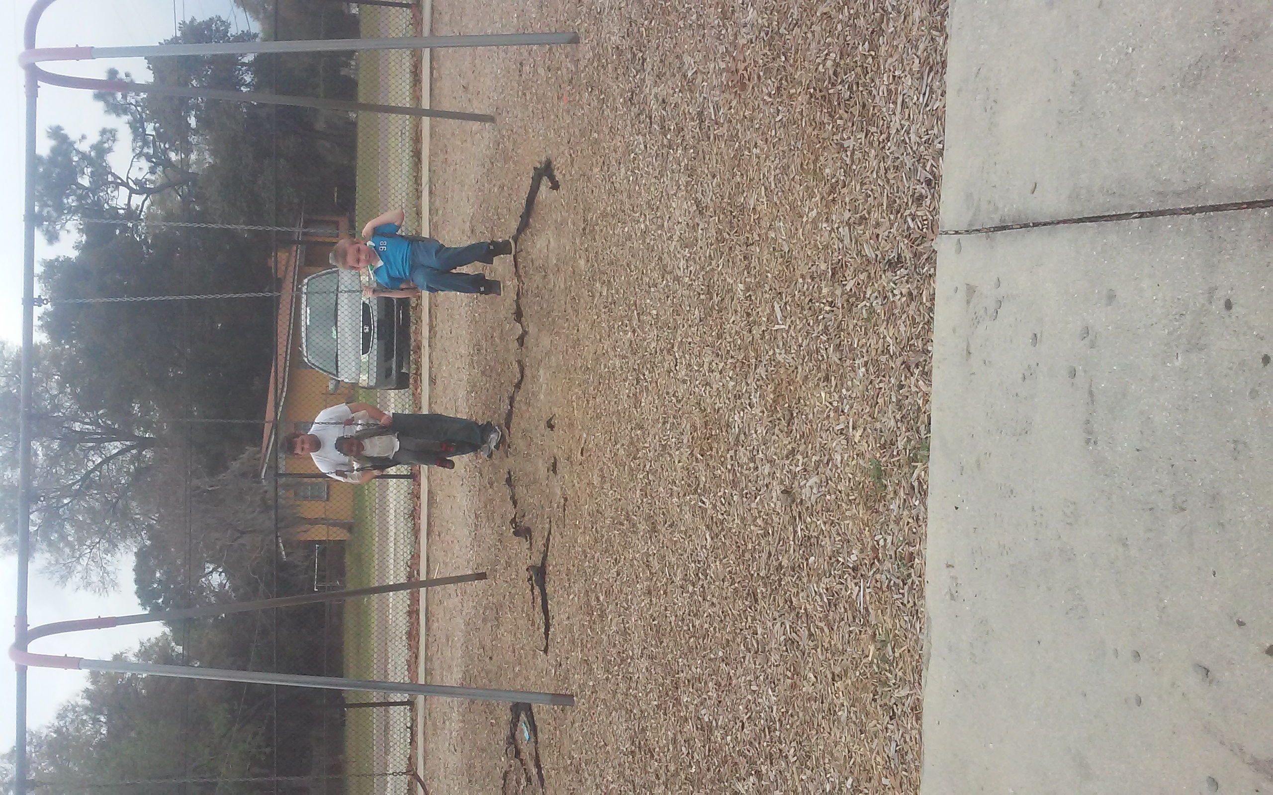 Husband pushing Kids on the swings