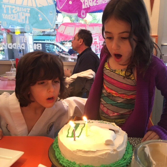Grandchildren blowing out candles on celebratory cake