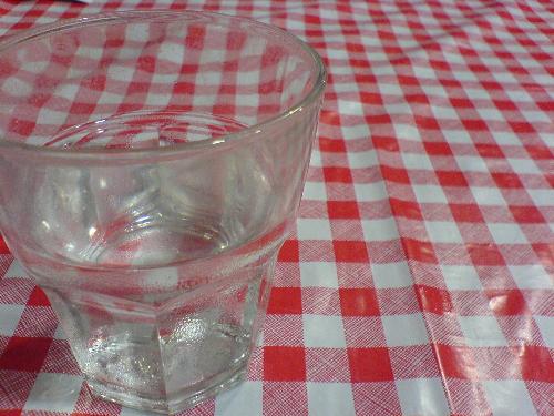 Glass on Table - A glass of water placed on the table covered by a piece of red and white checked tablecloth.