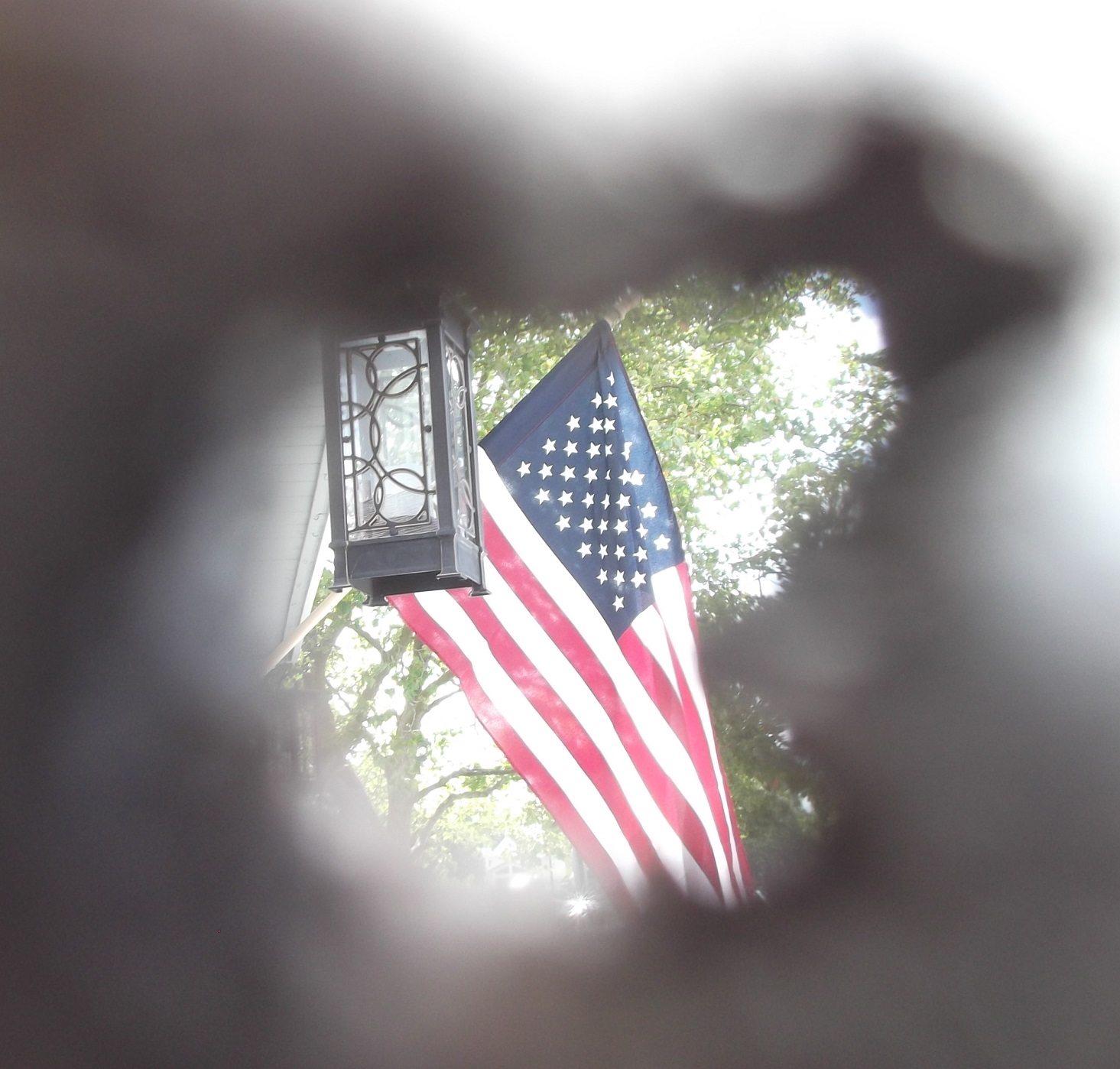 Photo I took of the flag in our neightbor's yard through a knothole in the fence at our mutual side yard/. Photo I took of the flag in our neightbor's yard through a knothole in the fence at our mutual side yard/.