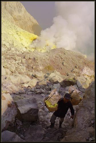 Do you have a cigaret? - Kawah IJen is 2,300 metres above sea-level. The enormous lake, which is 200 metres deep, contains approximately 36,000,000 cubic metres of steaming, acid water. A walk around the crater takes a full day. Sulphur is mined at the lake's edge and the average yield is nine to twelve tons per day. Experienced sulphur collectors, who are paid by weight, are able to transport loads of up to 90 kg to the top of the crater and then 17 km down the mountainside to Banyuwangi, mostly on foot. After arrival at the factory, the sulphur is treated for use in the production of medicines as well as for processing sugar.  The title of this picture is what this worker asked me after the picture... Unfortunatly for him, I am not a smoker... Anyway, I gave him some money because it's very hard to see them climming in the sulphur without filter mask while I had a one from the owner of Bromo hotel. Camera: Canon EOS 350D, Canon EF-S 18-55mm f/3.5-5.6, Compact Flash Exposure: f/11, 1/320 seconds