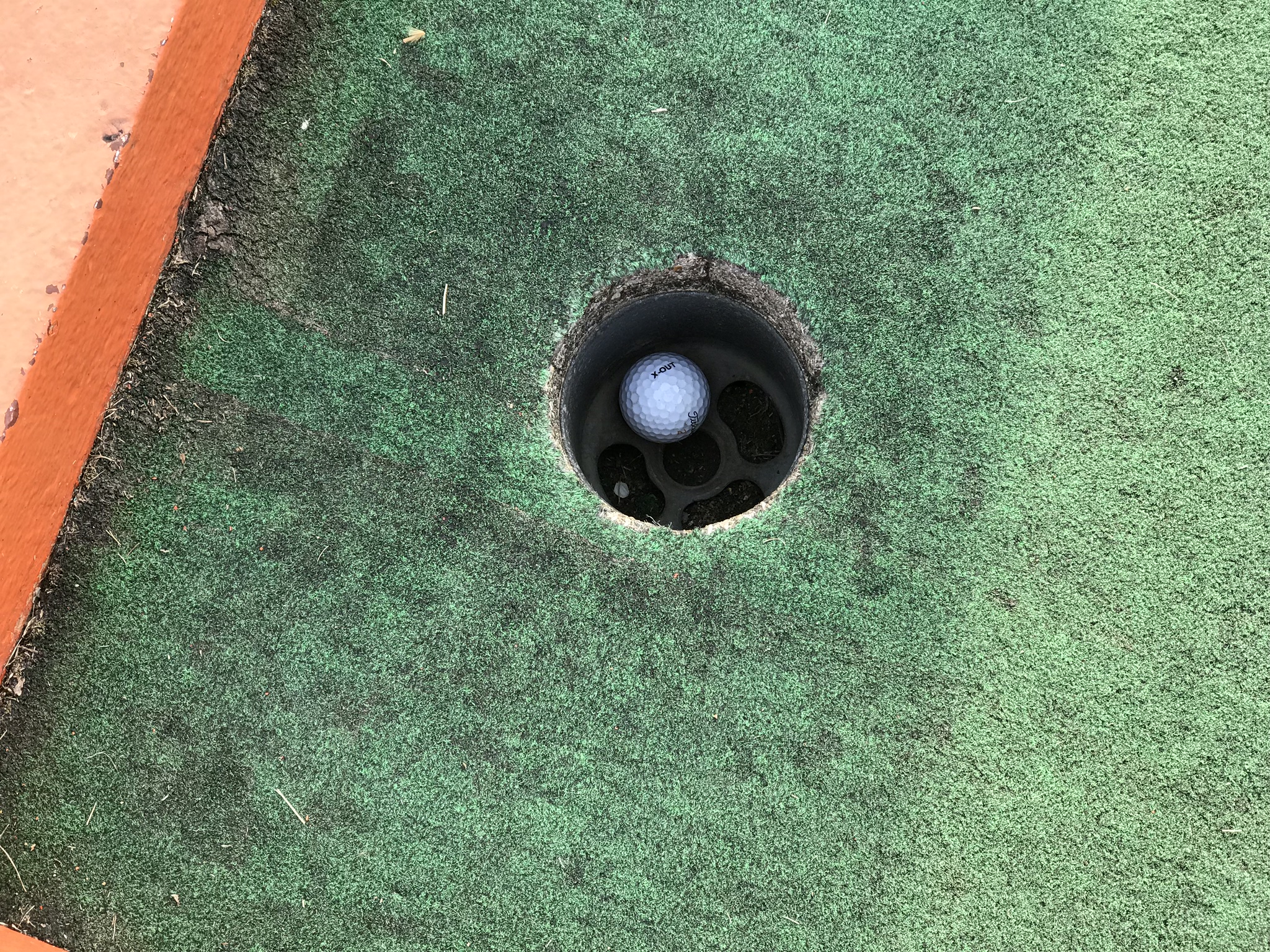A golf ball in the hole on course one.  Photo taken by and the property of FourWalls.