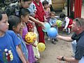 Children - Children standing in line being given colorful toys.