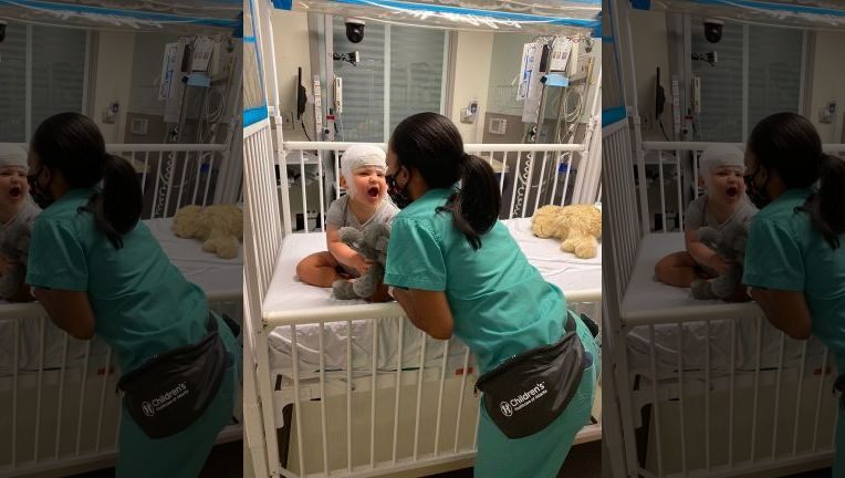 A nurse named Quanda enjoys entertaining a one year child in a hospital 