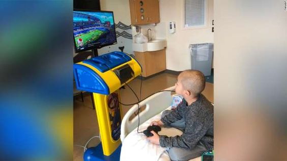 A young patient playing a video game inside of his hospital room A young patient playing a video game inside of his hospital room