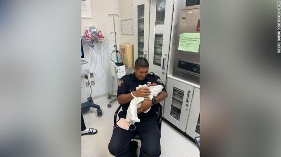 Jersey City police officer Eduardo Matute holding a 1 month infant he saved