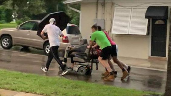 Four young men assist a lady who was riding a broken down scooter in Florida Four young men assist a lady who was riding a broken down scooter in Florida