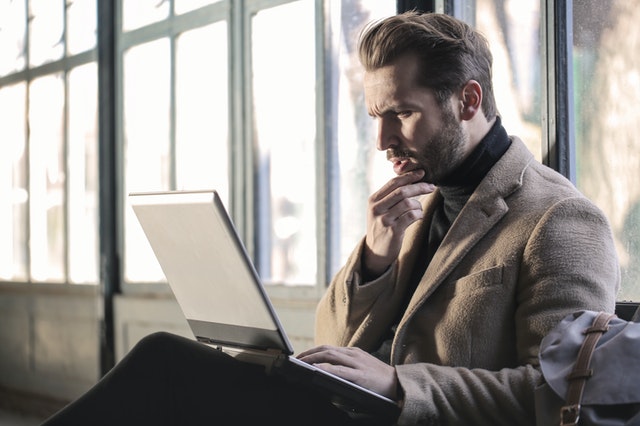 Man with a confused expression looking at his laptop