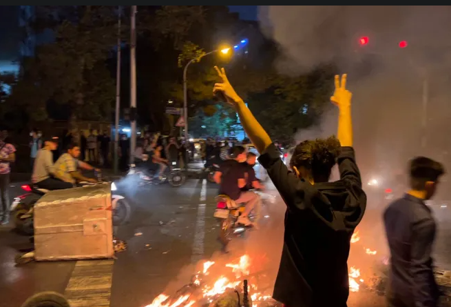 "A demonstrator raises his arms and makes the victory sign during a protest for Mahsa Amini, a woman who died after being arrested by the Islamic republic&#039;s &#039;minority police&#039;, in Tehran on September 19, 2022. / AFP Via Getty Images /