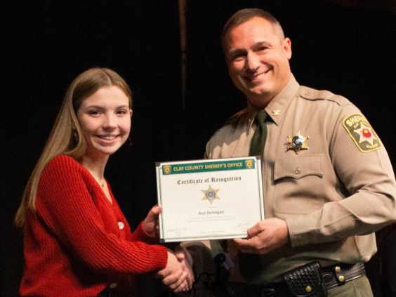 Ava Donegan receives an award form Clay County Sheriff Will Akin