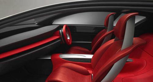 Interior - The interior of the Senku--Mazda calls it a 'prestigious environment'--is heavy on red, with clean lines and a clear disdain for backseat comfort. On-board cameras provide views of the outside world on three panels mounted above the dashboard; a display at the bottom of the instrument panel reports on the navigation, audio and air-conditioning systems. A touch screen inside the steering wheel is intended to provide easy control of the systems.  Credit: Mazda