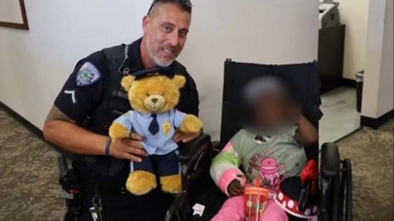 Officer Marzan with a teddy bear as he visits a young girl who was in an accident. 