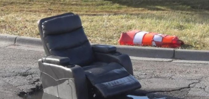 Black recliner on a pothole on a road in Grand Haven MIchigan.