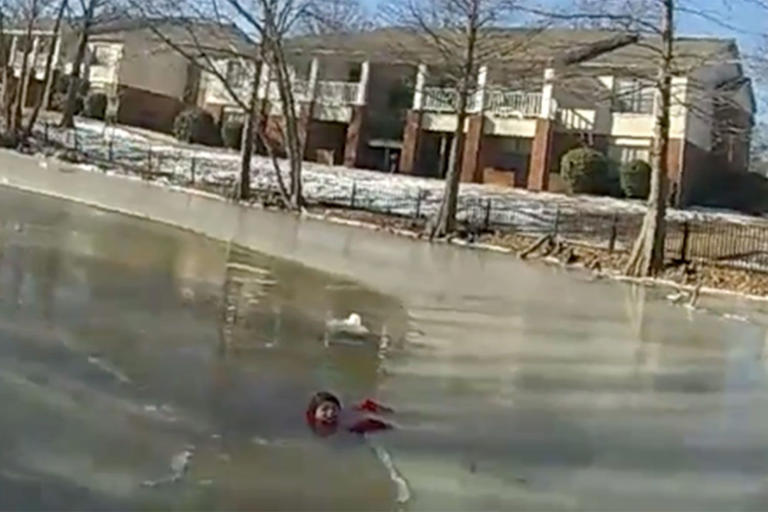 A child in a frozen pond ready to be rescued by a police officer and firefighters