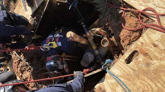 Firefighters rescue a plumber who fell down a trench.