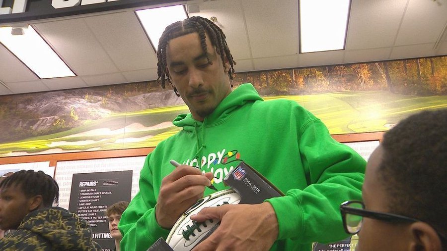 Green Bay Packers quarterback Jordan Love signing a football for a fan