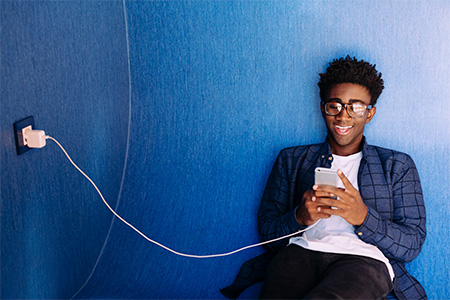 A person using a phone while charging it at the same time. Source: Ideal Credit Union Website