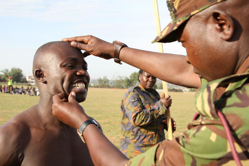A KDF recruiting officer checking a hopeful candidate&#039;s teeth during a past recruitment exercise