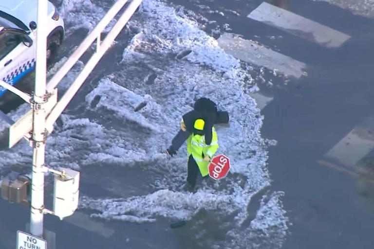 Crossing guard in Chicago carries a child across a flooded street