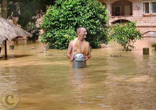 In flood - A ISKCON Swami Maharaj with container of dry food, Mayapur flood 2006