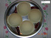 plain Idly - The idli, also romanized 'idly' or 'iddly', is made by steaming batter — traditionally made from pulses (specifically black lentils) and rice — into patties, usually two to three inches in diameter, using a mold. To prepare the classic idlis, two parts uncooked rice to one part split black lentil are soaked until they can be ground to a paste in a heavy stone grinding vessel, the attu kal. This paste is allowed to ferment overnight, until about 2-1/2 times its original volume. In the morning, the idli batter is put into the ghee-greased molds of an idli tray or 'tree' for steaming. This typically has several metal trays in tiers on a central support, with three or four round indentations per tray. These molds are perforated to allow the idlis to be cooked evenly. The tree holds the trays above the level of boiling water in a pot, and the pot is covered until the idlis are done, in 10-25 minutes, depending on size. The idli's pancake-like cousin is the dosa.