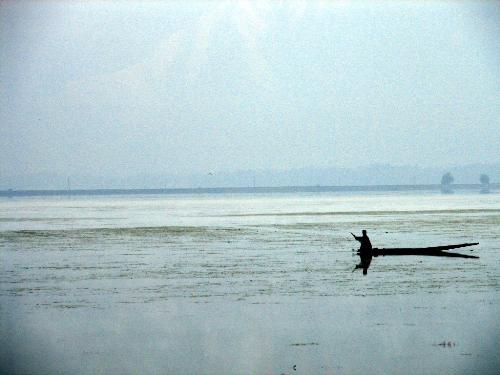 Dal Lake with Shikara - Early morning Dal Lake in Srinagar city with a boatman ferrying his shikara acroaa the lake. i was on my way to play tennis when i took this snap. This is the same day October 8th 2005, when a devastating earthquake shook the entire region. A great human tragedy. the photo was taken with a Canon S2IS