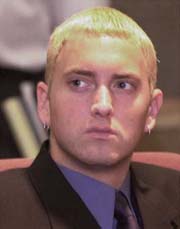 Eminem - Marshall Bruce Mathers III (born October 17, 1972) in Kansas City, Missouri, better known by his stage name Eminem, is a Grammy and Academy Award-winning American rapper, record producer and occasional actor.  He was born in Saint Joseph, Missouri,[1] and was raised in Warren, Michigan. His talents were discovered by rapper and producer Dr. Dre, Eminem got his big break when he signed with Dre's Aftermath Entertainment, becoming a crossover sensation with his debut single 'My Name Is' and simultaneously earning respect for his technical and lyrical ability.  Eminem is noted for his ability to change his vocal pace and style multiple times within one song without losing the beat, and has been praised for his skill in alliteration and assonance. He's also infamous for the controversy surrounding many of his lyrics. With the enormous success of his highly acclaimed album The Marshall Mathers LP and its subsequent nomination for four Grammy awards including Album of the Year, critics such as GLAAD denounced his lyrics as homophobic and misogynist, while others protested that it promoted violence.  The most recent release from Aftermath was a greatest hits album from Eminem called Curtain Call: The Hits in 2005, a compilation covering many of his previous commercial hit songs, in addition to three new tracks. Mathers has stated that he is taking a break from solo work, but is in no way retiring as he continues to produce and collaborate with his fellow Aftermath artists as well as G-Unit artists and rappers under his Shady Records label.  To date, Eminem has sold around 77 million albums worldwide.  By most accounts, the Mathers family was poor. They moved constantly, during which Marshall and his mother often lived in trailers, mobile homes, and under the care of relatives. From time to time they also lived in their car, and in fact this is where Eminem's little brother Nathan Samra-Mathers, was born. During this time, Debbie Mathers was taking the prescription medications Vicodin and Valium; Marshall Mathers later claimed in numerous interviews and songs that his mother was abusing the drugs,[2] to which she retaliated with a lawsuit pressing defamation charges (see below). In the song 'Cleaning Out My Closet' (The Eminem Show, 2002), Mathers also accuses his mother of having Munchausen syndrome by proxy, adding that 'my whole life I was made to believe I was sick when I wasn't.' This was not the first time someone had suggested she had the disorder; a social worker had made similar comments following a 1996 investigation of her mistreatment of Nathan.  Mathers was especially close to his uncle, Ronald 'Ronnie' Polkingharn, who was born just three months before him on July 27, 1972. Polkingharn introduced Mathers to hip-hop and the two were best friends. On December 14, 1991, 19-year-old Polkingharn committed suicide, an event which Mathers has said was devastating, not just to him but to the entire extended family. Ronnie Nelson's older brother Steven suffered a stroke as a result of the stress. Mathers was so distraught he abandoned his musical career for a year. References to Ronnie's death appear in several songs, including 'Stan', 'Cleaning Out My Closet', 'Mockingbird,' 'How Come,' (by D12) and 'My Dad's Gone Crazy.' Mathers has a tattoo on his upper left arm that says 'Ronnie R.I.P.'  Before dropping out of Lincoln High School in Warren at the age of 17 after failing ninth grade three times, Mathers made a number of significant acquaintances at the school, including Evan Perks, a three-time chess champion who was shot in a drive by, the late rapper Proof, who was to become one of his closest friends, and future wife Kimberly Ann 'Kim' Scott, with whom he soon developed a long-term relationship. When she became pregnant, Mathers started working on getting a record deal to support his new family; He discusses this in 'Never 2 Far' (Infinite, 1996), saying 'I got a baby on the way, I don't even got a car...I still stay with my moms...we gotta make some hit records or something [because] I'm tired of being broke...' When the Infinite album failed to generate the revenue and acclaim he had hoped for, she ended their relationship, preventing him from seeing his newborn child, a daughter named Hailie Jade Scott (born December 25, 1995); distraught, he attempted suicide with an overdose of Tylenol. After the attempt failed, he resumed his efforts to succeed in the music industry and reconcile with his ex-girlfriend.(Linda Swanna) [3] He ultimately succeeded in doing both, marrying her on June 14, 1999, in Saint Joseph, Missouri. Mathers would go on to mention his daughter extensively in some of his songs, including ''97 Bonnie & Clyde' (The Slim Shady LP, 1999), which takes the form of a one-sided dialogue with Hailie, as well as 'Hailie's Song' (The Eminem Show, 2002), 'Mockingbird' (‘‘Encore’’, 2004), and 'When I'm Gone' (Curtain Call: The Hits, 2005), all of which are proclamations of his love and dedication to her. In addition, he samples her voice in the track 'My Dad's Gone Crazy' (The Eminem Show, 2002).